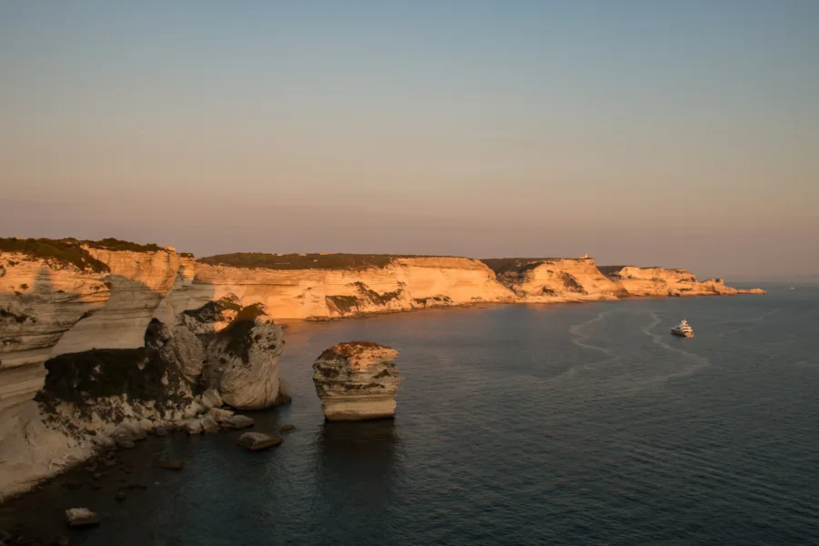 Falaises calcaires de Bonifacio dans la lumière rasante du soir, avec le rocher isolé du Grain de Sable au premier plan (août 2016).