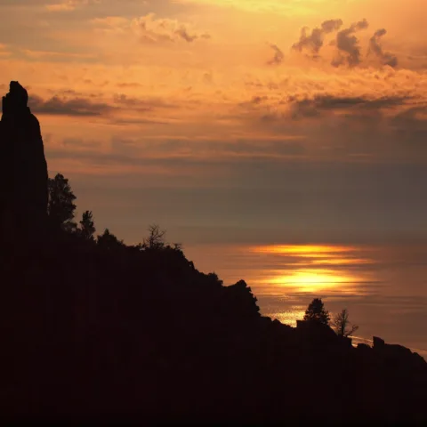Coucher de soleil sur le golfe de Porto ; à gauche en silhouette, le rocher dit « des Amoureux » des Calanche de Piana.