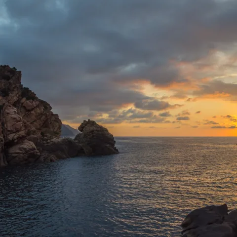 La tour génoise de Porto sur son rocher au coucher du soleil, soleil bas sur le golfe de Porto.