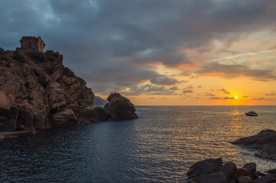 La tour génoise de Porto sur son rocher au coucher du soleil, soleil bas sur le golfe de Porto.
