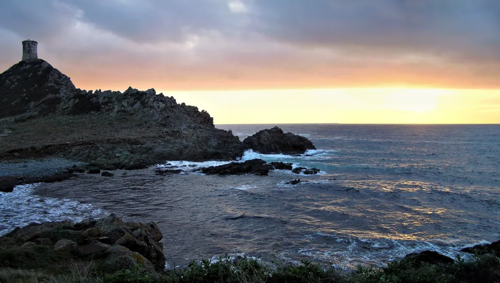 Coucher de soleil à la pointe de la Parata face au large, la tour génoise de la Parata en silhouette à gauche.
